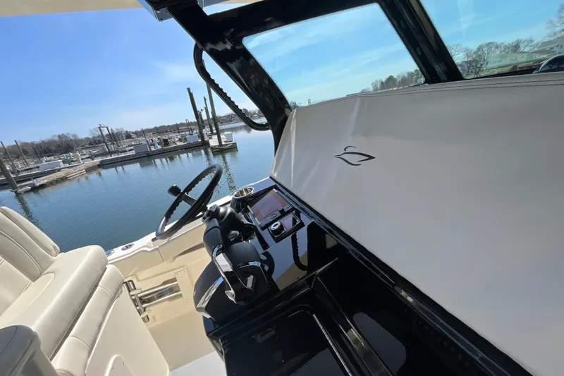 Slide: The Image of 2025 Scout 330 LXF boat interior with steering wheel and dashboard, docked at marina. - 16