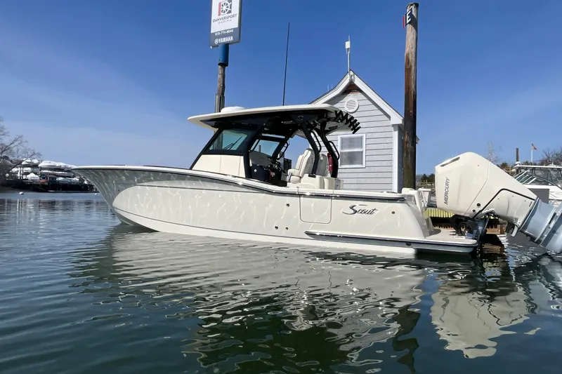 Slide: The Image of 2025 Scout 330 LXF boat docked on calm water under clear blue sky. - 2