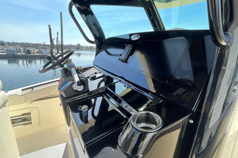 Slide: The Image of 2025 Scout 330 LXF boat dashboard with steering wheel and controls, docked by the water. - 20