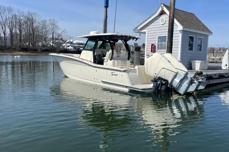Slide: The Image of 2025 Scout 330 LXF boat docked at marina with calm water reflection. - 4