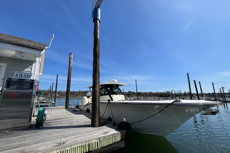 Slide: The Image of 2025 Scout 330 LXF boat docked at marina under clear blue sky. - 6