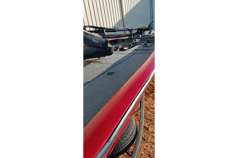 Slide: The Image of 2025 Tracker Pro Team 190 boat deck with red trim, parked outdoors. - 13