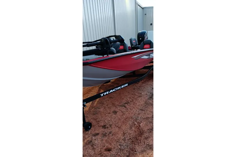 Slide: The Image of 2025 Tracker Pro Team 190 boat in red, parked on a trailer beside a building. - 16