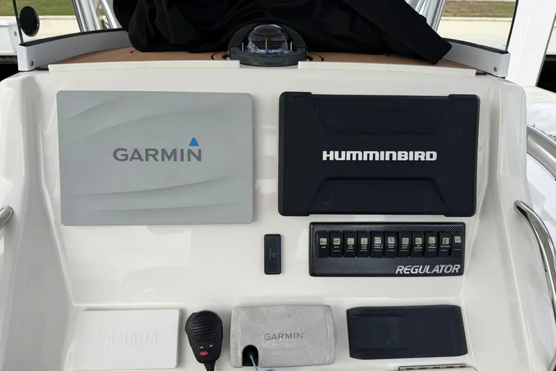 Slide: The Image of 2015 Regulator 25 boat T-top with speakers and lights, docked near palm trees. - 27