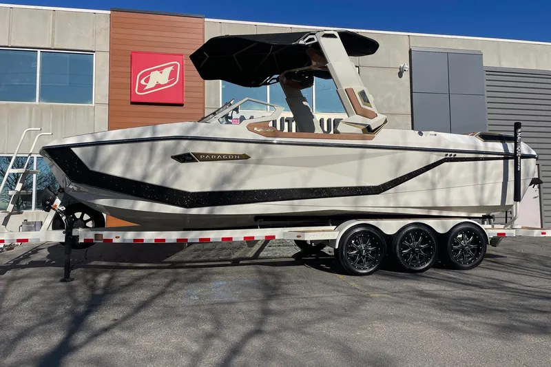 The Image of 2025 Nautique Super Air Nautique G25 Paragon boat on trailer outside dealership. - 1