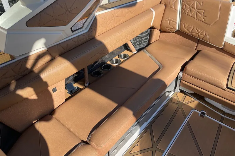Slide: The Image of 2025 Nautique Super Air Nautique G25 Paragon interior with luxurious brown seating and cup holders. - 7