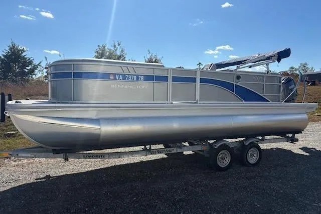 The Image of 2025 Bennington 22SXSR pontoon boat on trailer under clear blue sky. - 1