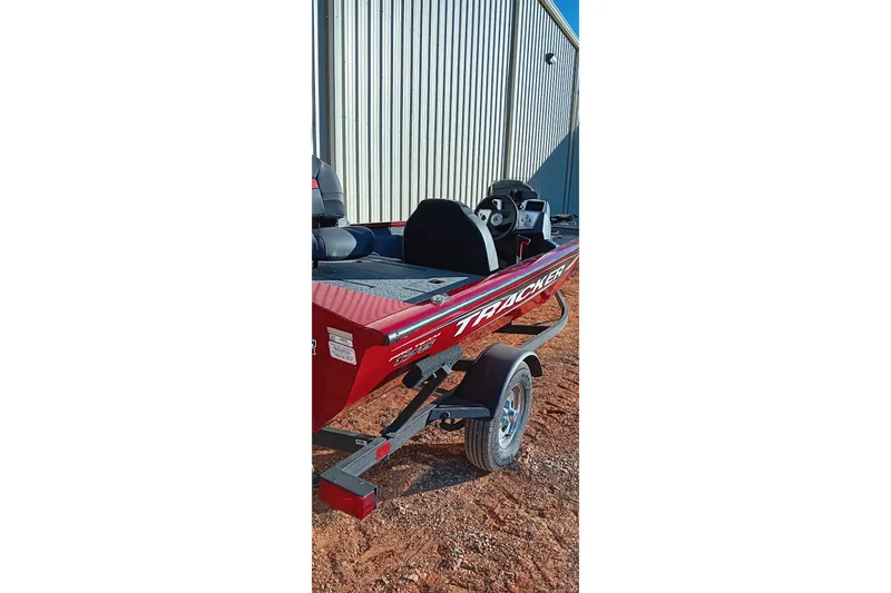 Slide: The Image of 2025 Tracker Pro Team 175 boat on trailer, parked beside a metal building. - 3
