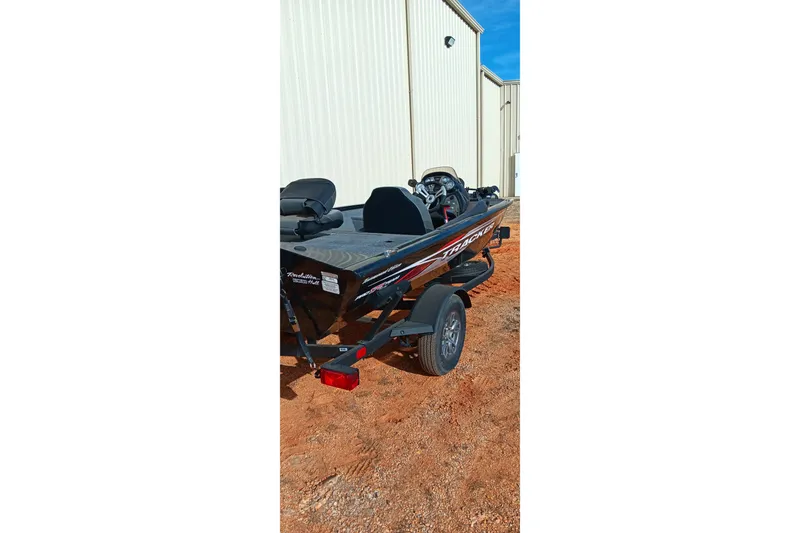 Slide: The Image of 2024 Tracker Pro Team 175 TXW boat on trailer, parked near a building. - 16
