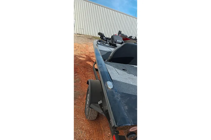 Slide: The Image of 2024 Tracker Pro Team 175 TXW boat on trailer, parked on dirt near a building. - 17