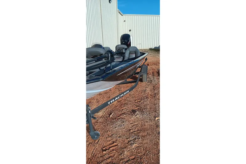 Slide: The Image of 2024 Tracker Pro Team 175 TXW boat on trailer, parked on dirt near a building. - 9