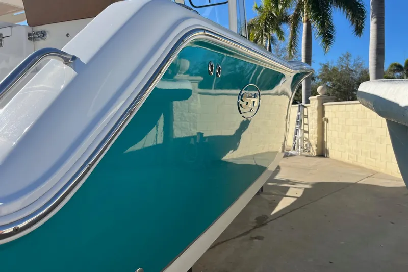 Slide: The Image of 2021 Sea Hunt Gamefish 27 Coffin Box boat with teal hull, docked near palm trees. - 4