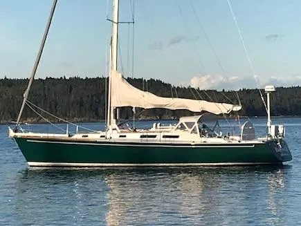 The Image of 1989 J Boats J/44 sailboat with green hull, anchored on calm water. - 0