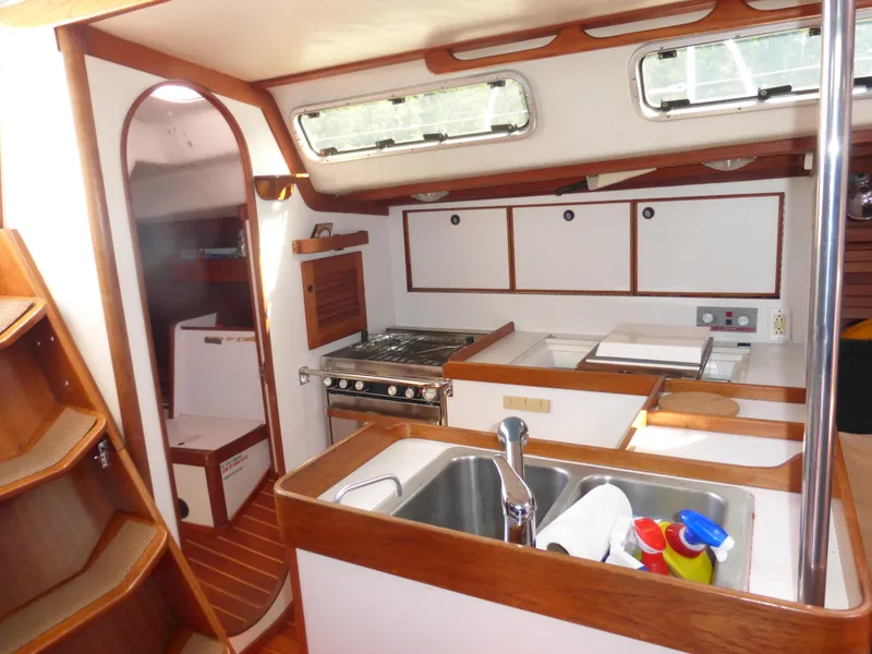 Slide: The Image of Interior of 1989 J Boats J/44 sailboat, featuring a compact kitchen with wood accents. - 19