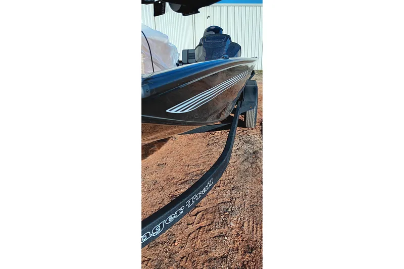 Slide: The Image of 2026 Ranger RT198P boat on trailer, parked on dirt near a white building. - 11