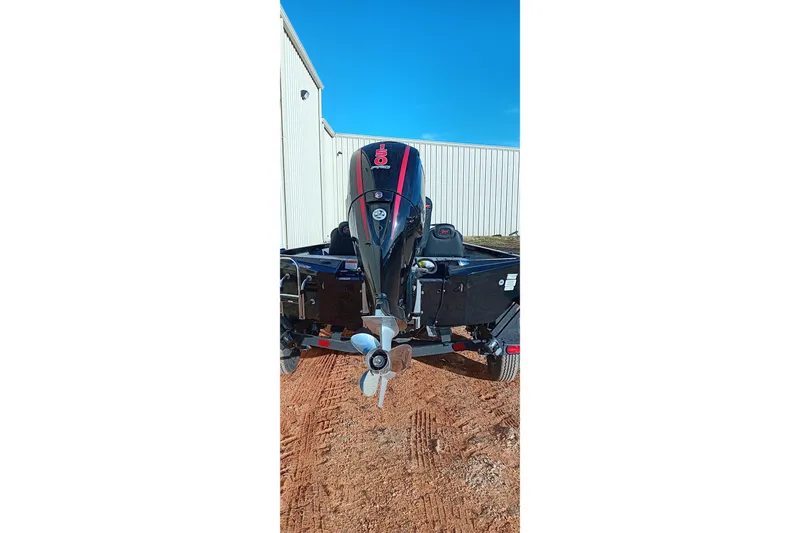 Slide: The Image of 2026 Ranger RT198P boat with powerful outboard motor, parked on dirt near a building. - 2