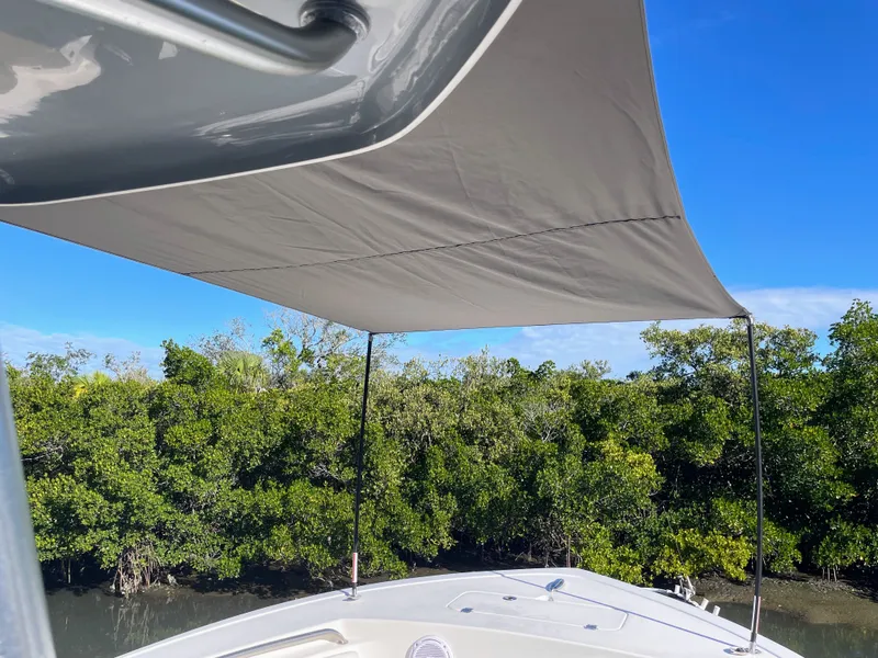 Slide: The Image of 2017 Tidewater 220 boat with sunshade, surrounded by lush greenery. - 43