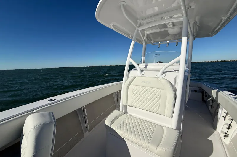 Slide: The Image of 2026 Jupiter 26 boat interior with cushioned seating, navigating on open water under clear blue sky. - 15