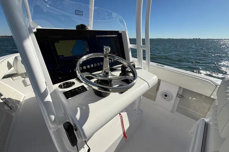 Slide: The Image of Steering console of 2026 Jupiter 26 boat with navigation screens, on open water. - 17