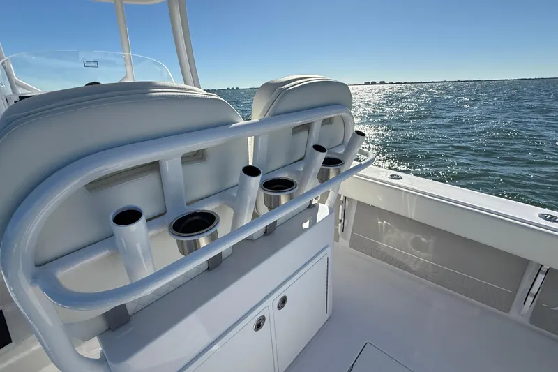 Slide: The Image of 2026 Jupiter 26 boat interior with rod holders, ocean view, and clear blue sky. - 23