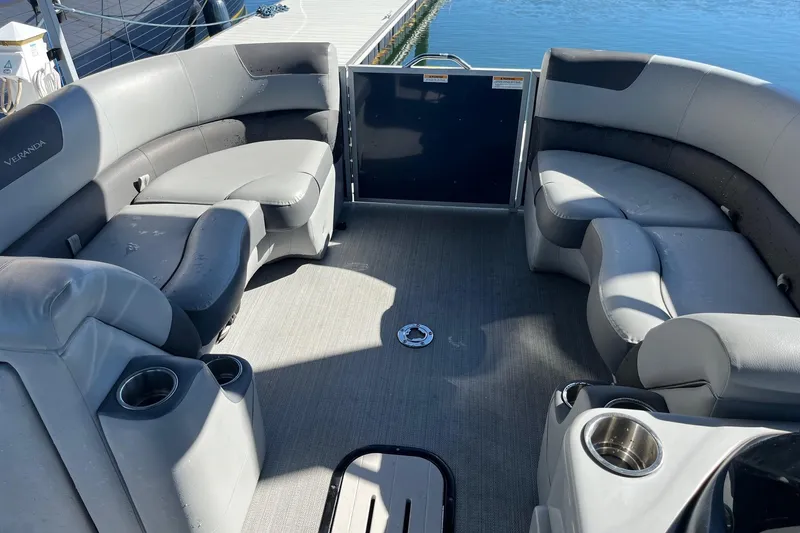 Slide: The Image of 2023 Veranda Relax VR22RC pontoon boat interior with gray seating and cup holders. - 2