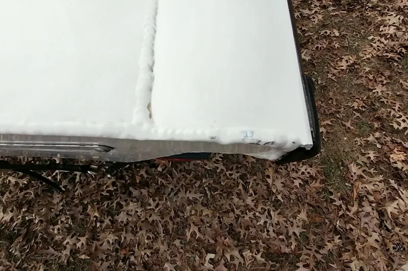 Slide: The Image of 2022 Tracker Pro Team 195 TXW boat covered in white tarp, surrounded by autumn leaves. - 18