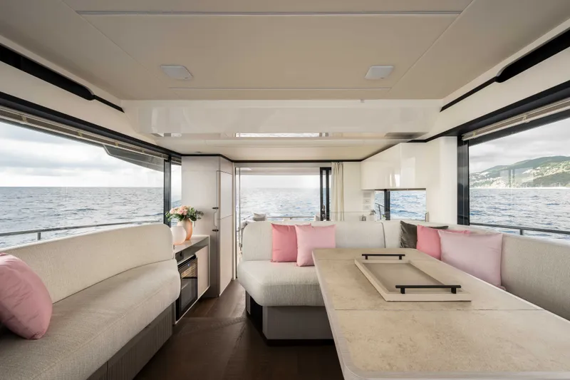 Slide: The Image of Interior of a luxury yacht with beige sofas and pink cushions, surrounded by large windows overlooking the sea. - 24