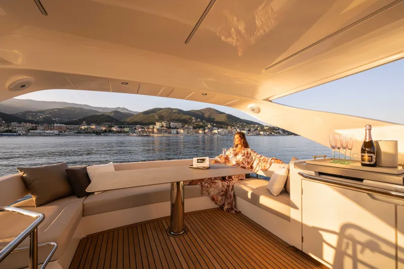 Slide: The Image of A woman relaxes on a luxurious boat overlooking a coastal town at sunset. - 19
