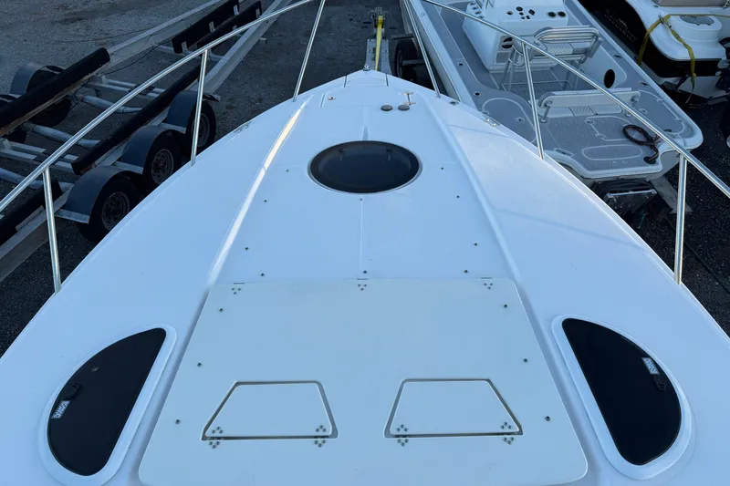 Slide: The Image of 2019 Regal 33 OBX boat deck with railings and hatch, docked beside trailers. - 14