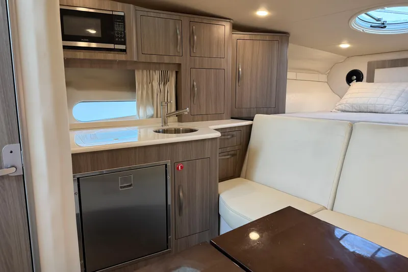 Slide: The Image of 2019 Regal 33 OBX cabin interior with kitchenette, seating, and bed. - 24