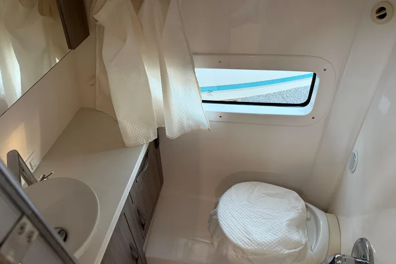 Slide: The Image of 2019 Regal 33 OBX boat bathroom with sink, toilet, and window. - 31