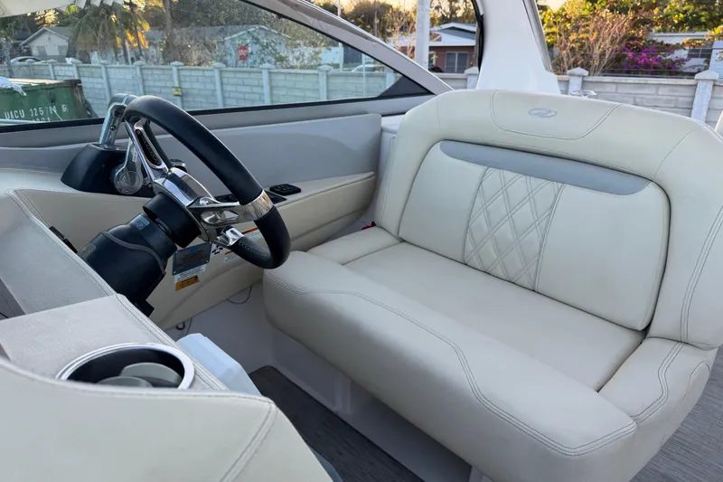 Slide: The Image of 2019 Regal 33 OBX boat interior with steering wheel and beige seating. - 35