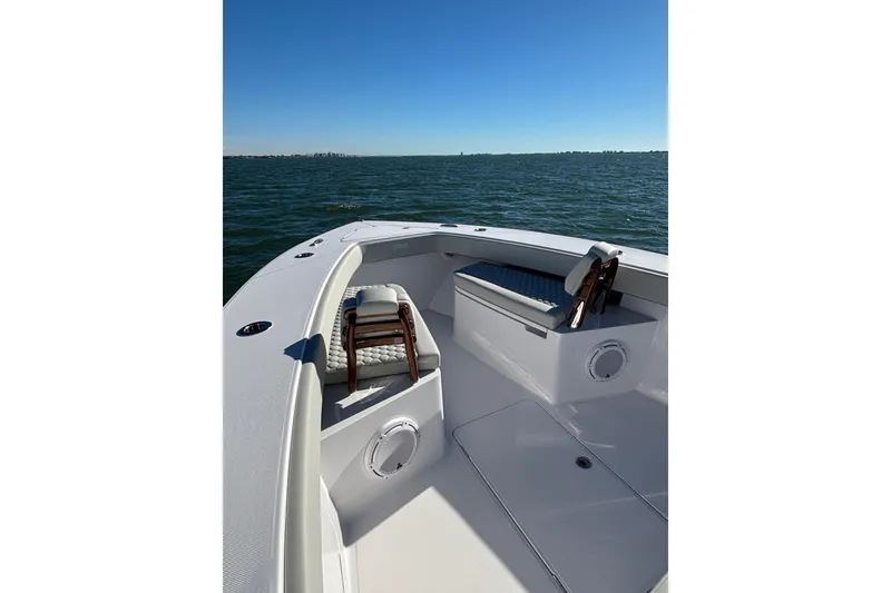 Slide: The Image of 2026 Jupiter 32 boat interior with seating, on calm water under clear blue sky. - 19