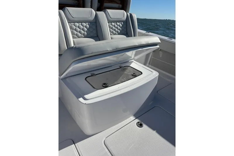 Slide: The Image of 2026 Jupiter 32 boat seat with storage compartment open on a sunny day. - 26