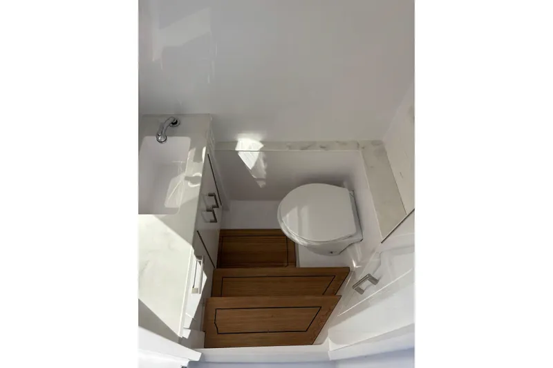 Slide: The Image of Compact bathroom in 2026 Jupiter 32 model, featuring a toilet and sink with wooden flooring. - 32