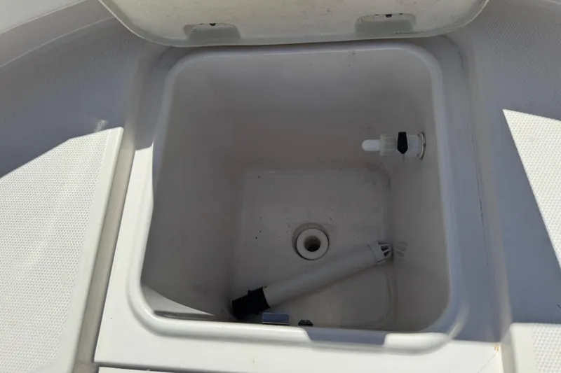 Slide: The Image of 2022 Robalo R242 Center Console storage compartment with open lid and drain plug. - 11