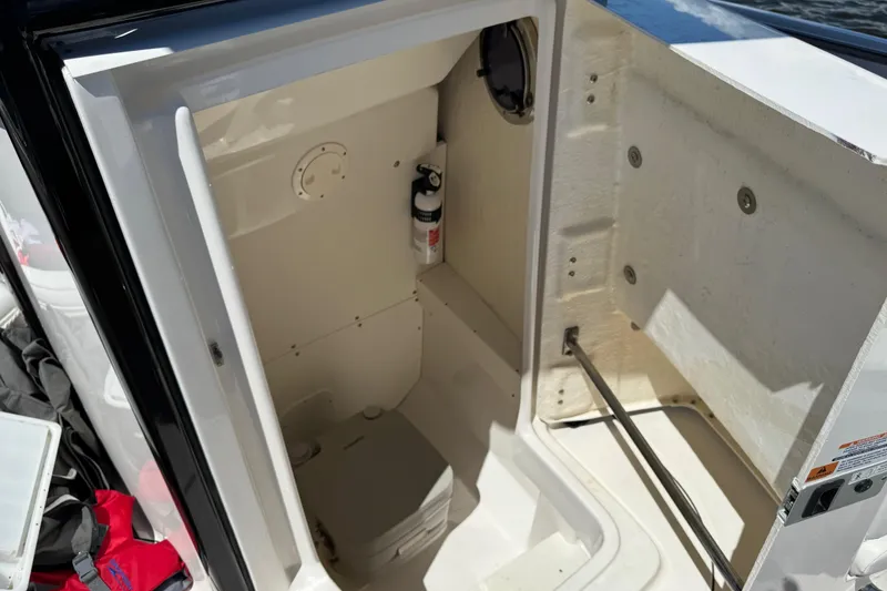 Slide: The Image of 2022 Robalo R242 Center Console boat interior with storage compartment and fire extinguisher. - 12