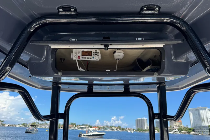 Slide: The Image of 2022 Robalo R242 Center Console boat with open electronics compartment, scenic waterfront view. - 15