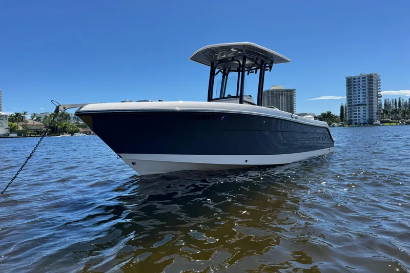 Slide: The Image of 2022 Robalo R242 Center Console boat on water, with cityscape background. - 2