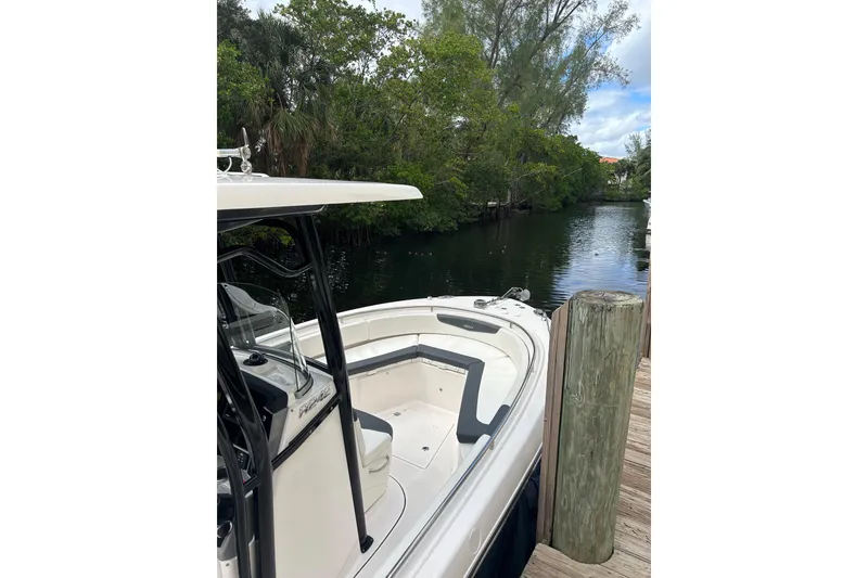 Slide: The Image of 2022 Robalo R242 Center Console boat docked by a serene riverbank. - 7
