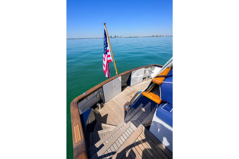 Slide: The Image of Deck view of 1986 Jongert 85 yacht with American flag, calm sea, and distant cityscape. - 45