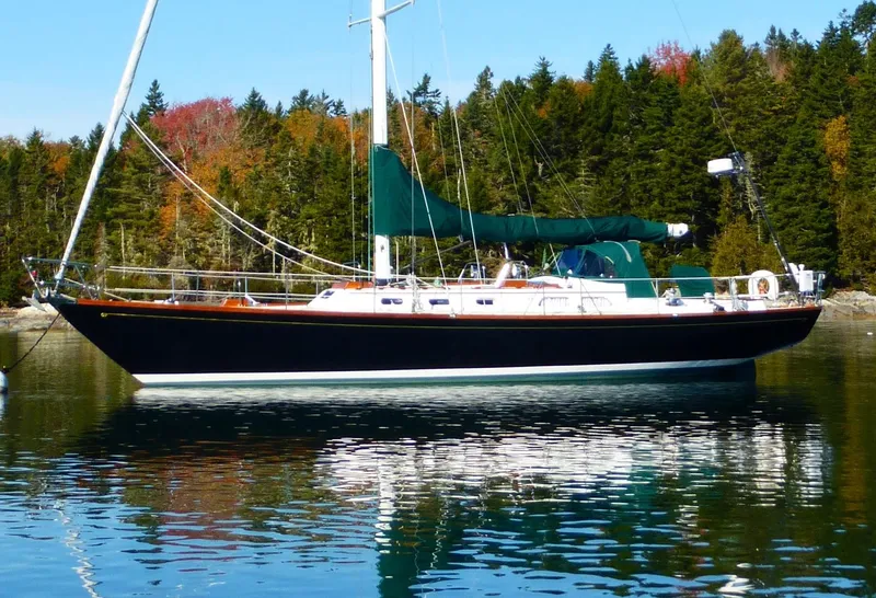 The Image of 1986 Hinckley Sou'wester 51 sailboat on calm water, surrounded by autumn trees. - 0
