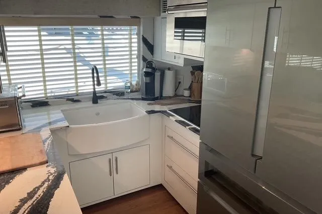 Slide: The Image of Modern kitchen interior on 1997 Hatteras 70 Sport Deck Motor Yacht, featuring sleek appliances and ample lighting. - 12