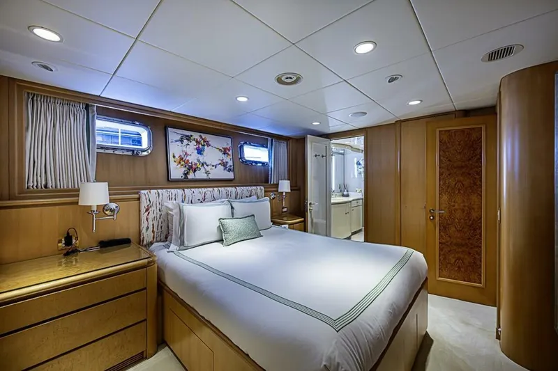 Slide: The Image of Luxurious bedroom interior on 1997 Delta 122 Tri-Deck Motor Yacht, featuring elegant wood paneling. - 50