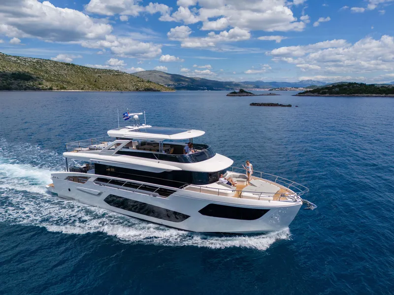 Slide: The Image of 2026 Absolute Navetta Co Ownership yacht cruising on clear blue waters under a partly cloudy sky. - 2