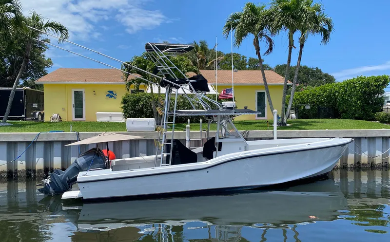 The Image of Ocean Master 3100 boat docked by waterfront homes, palm trees, and clear sky. - 1
