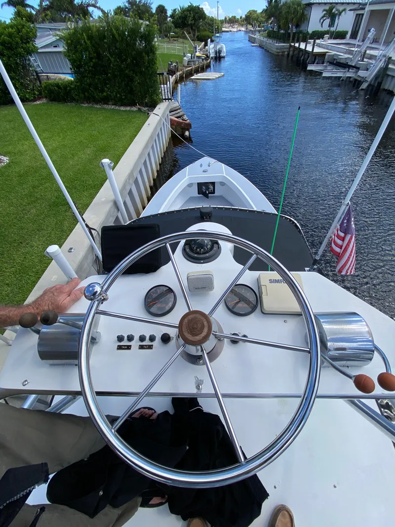 Slide: The Image of View from Ocean Master 3100 boat helm, navigating a canal, American flag visible, 1995 model. - 18