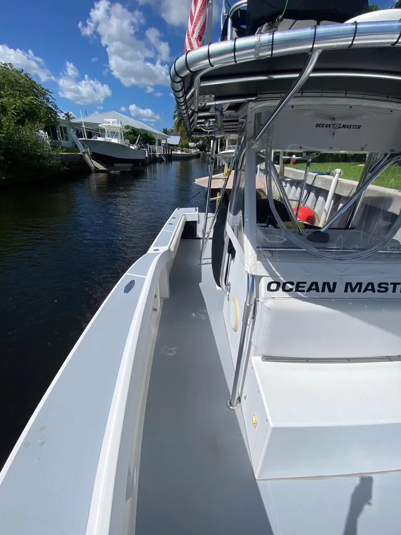 Slide: The Image of 1995 Ocean Master 3100 boat docked on a sunny day, featuring spacious deck and canopy. - 5