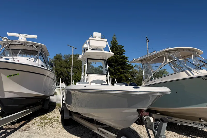 Slide: The Image of 2020 Robalo 246 Cayman SD boat on trailer, flanked by two other boats. - 0
