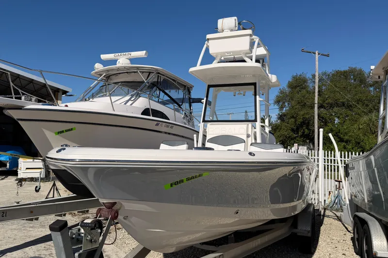 Slide: The Image of 2020 Robalo 246 Cayman SD boat for sale, parked on a trailer in a marina. - 1